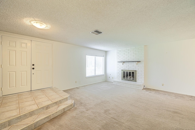 unfurnished living room featuring carpet, visible vents, a fireplace, and a textured ceiling