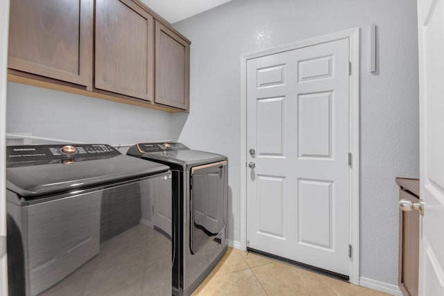 laundry room with cabinets, light tile patterned floors, and washer and clothes dryer