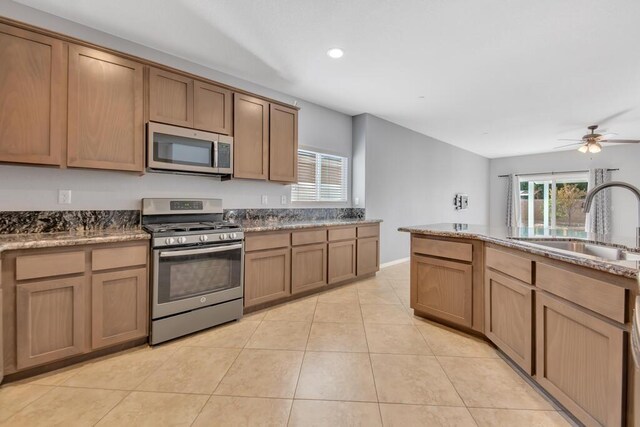 kitchen featuring sink, ceiling fan, light stone countertops, light tile patterned floors, and appliances with stainless steel finishes