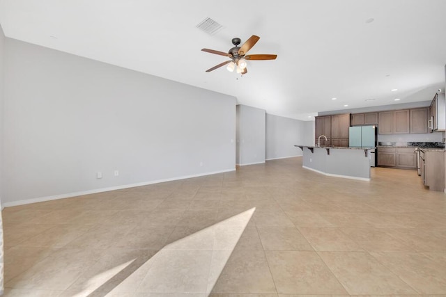 unfurnished living room featuring ceiling fan, light tile patterned floors, and sink