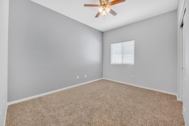 empty room featuring ceiling fan and carpet