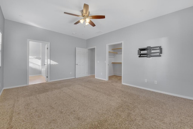 unfurnished bedroom featuring a walk in closet, ceiling fan, connected bathroom, light colored carpet, and a closet