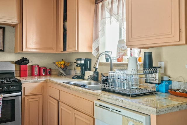 kitchen featuring white dishwasher, sink, light brown cabinetry, and stainless steel gas range