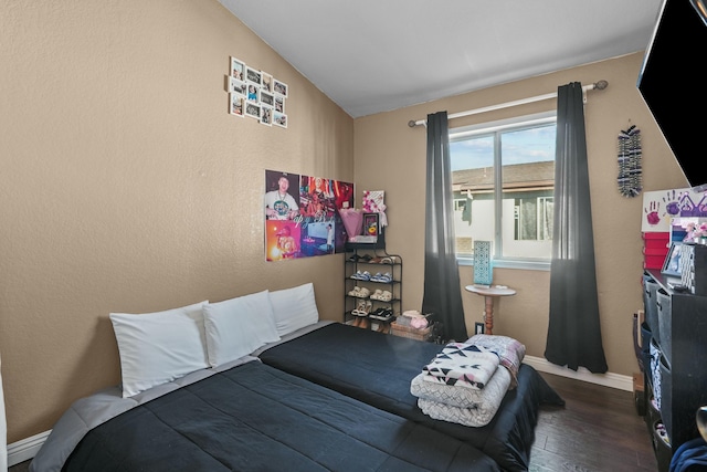 bedroom with vaulted ceiling and dark wood-type flooring