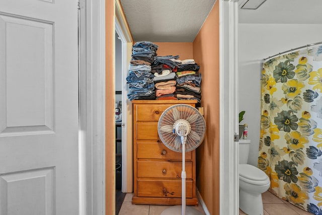 bathroom featuring curtained shower, tile patterned flooring, a textured ceiling, and toilet