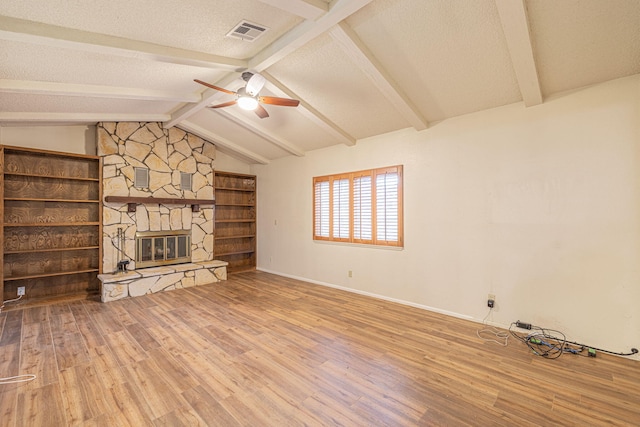 unfurnished living room with hardwood / wood-style floors, a fireplace, lofted ceiling with beams, ceiling fan, and a textured ceiling