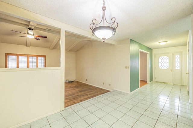 unfurnished room with beamed ceiling, light tile patterned flooring, ceiling fan, and a textured ceiling