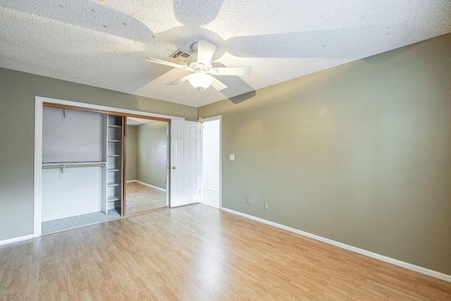 unfurnished bedroom featuring a closet, ceiling fan, a textured ceiling, and light hardwood / wood-style flooring