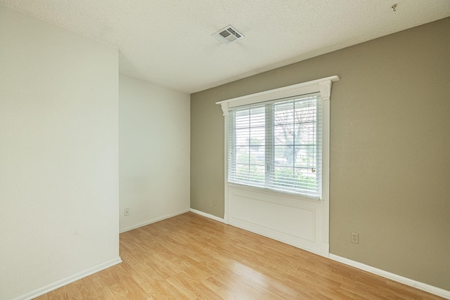 spare room with light hardwood / wood-style flooring and a textured ceiling