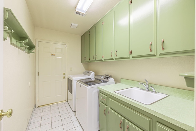 laundry area with sink, light tile patterned floors, washing machine and dryer, and cabinets