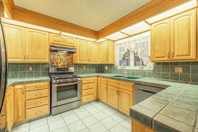 kitchen with sink, decorative backsplash, light tile patterned floors, tile counters, and stainless steel appliances