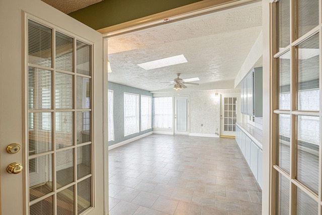 unfurnished sunroom with ceiling fan and a skylight