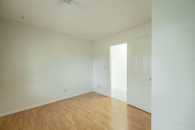 spare room with light hardwood / wood-style floors and a textured ceiling