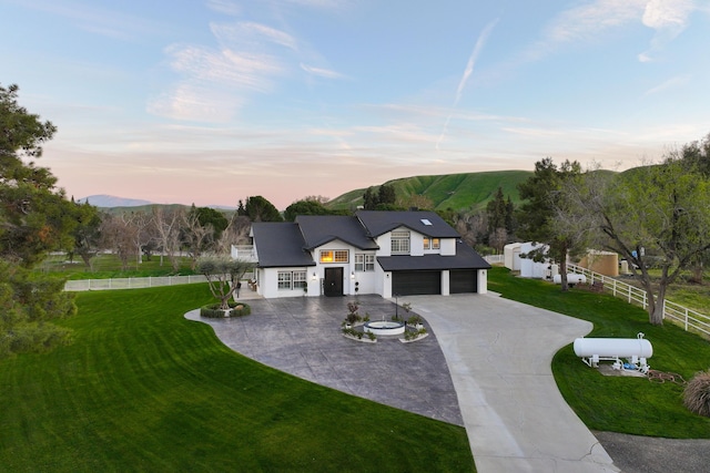 modern farmhouse featuring a front yard, fence, driveway, a garage, and a mountain view