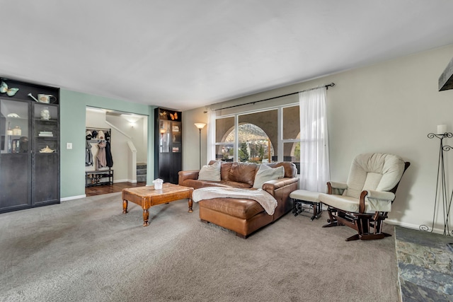 carpeted living area with stairway and baseboards