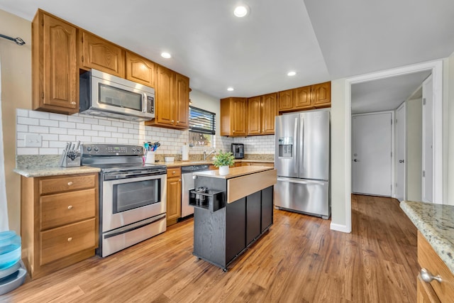 kitchen with brown cabinets, light wood-style floors, stainless steel appliances, and backsplash