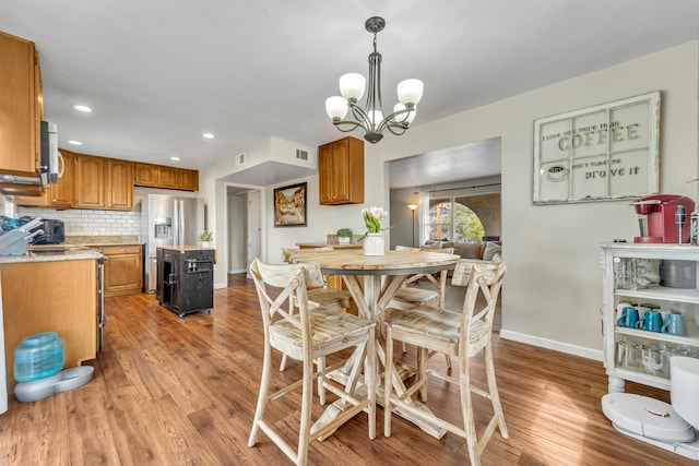 dining area featuring a chandelier, visible vents, baseboards, and wood finished floors