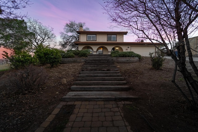 exterior space featuring stairway, a chimney, an attached garage, and stucco siding