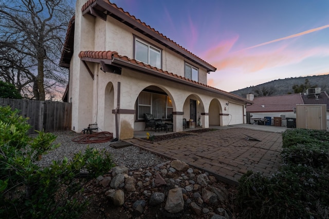 back of property featuring a garage, fence, driveway, a tiled roof, and stucco siding