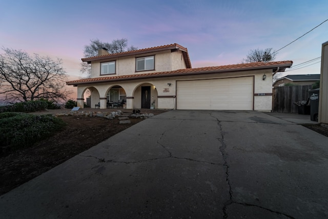 mediterranean / spanish house featuring driveway, a garage, a chimney, a porch, and stucco siding