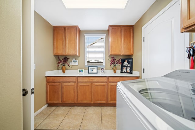 clothes washing area featuring light tile patterned flooring, cabinets, and washer / dryer