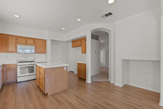 4349 Bethpage Dr, Palmdale, CA 93551 - kitchen featuring white appliances, arched walkways, light wood-style floors, a center island, and recessed lighting