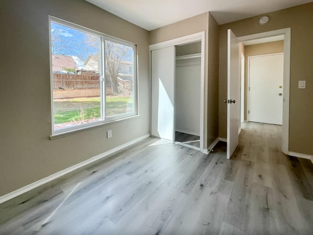 unfurnished bedroom with a closet, baseboards, and wood finished floors