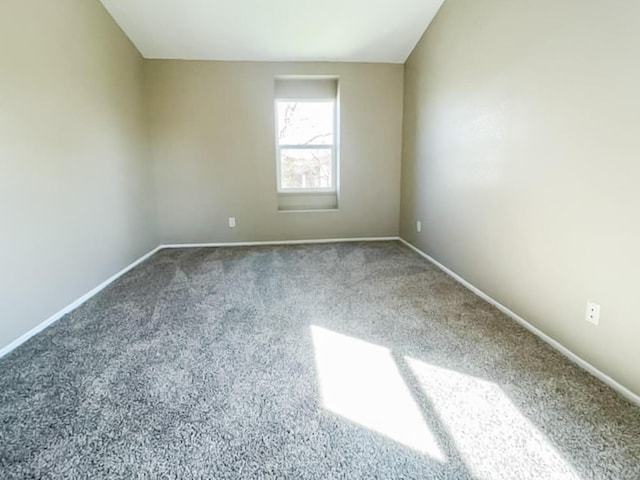 carpeted spare room featuring baseboards