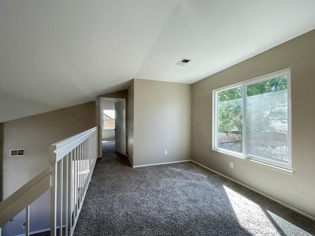 carpeted empty room featuring visible vents, lofted ceiling, and baseboards