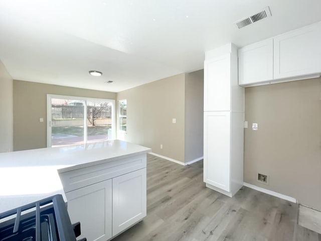 kitchen with white cabinetry, light countertops, light wood-style flooring, and visible vents