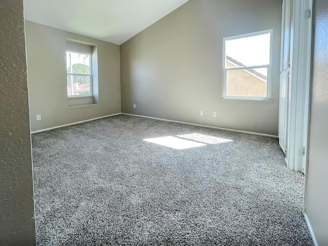 unfurnished room featuring lofted ceiling, carpet flooring, and baseboards