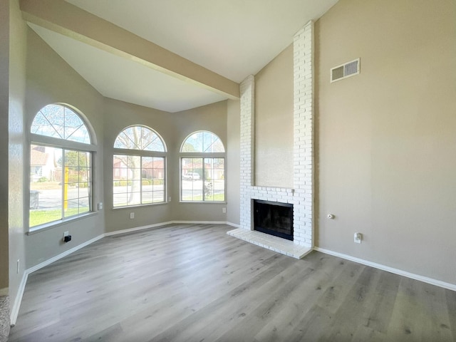 unfurnished living room featuring visible vents, high vaulted ceiling, baseboards, and wood finished floors