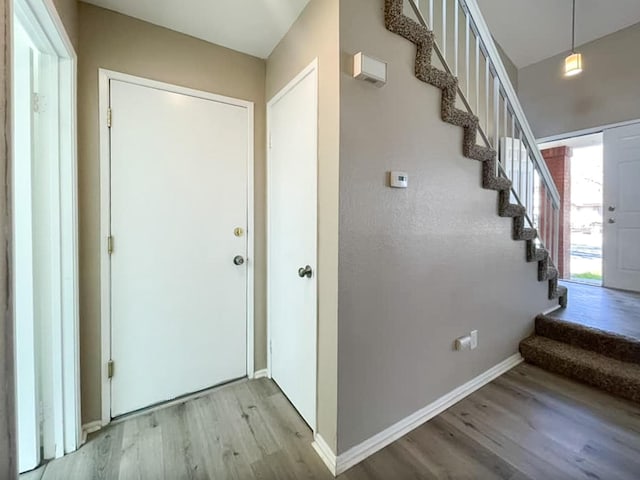 foyer entrance with stairs, baseboards, and wood finished floors