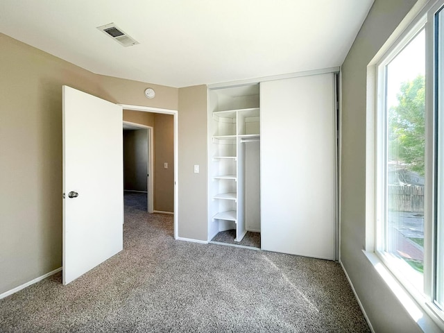 unfurnished bedroom featuring carpet flooring, baseboards, visible vents, and a closet