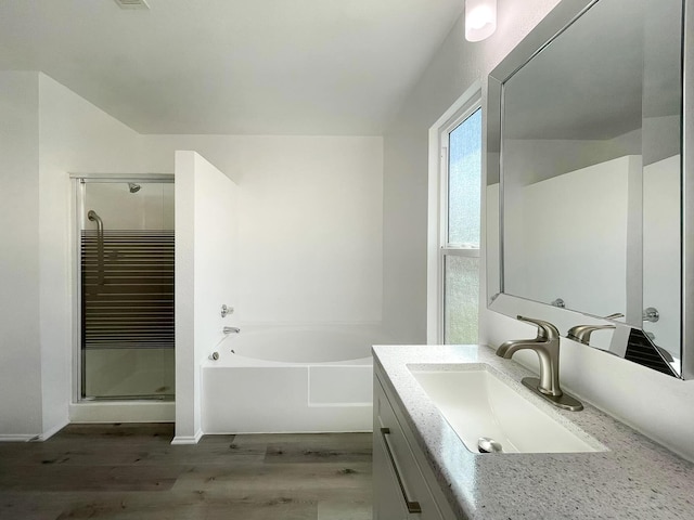 full bathroom with a stall shower, vanity, a garden tub, and wood finished floors