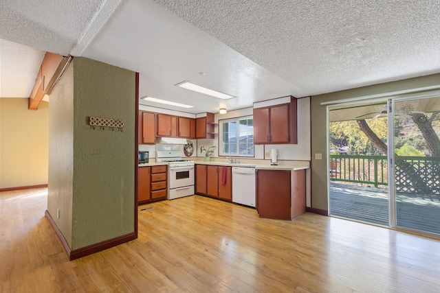 kitchen with white appliances, a textured ceiling, and light wood-type flooring