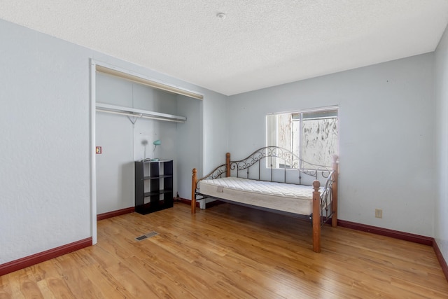 bedroom featuring hardwood / wood-style flooring, a closet, and a textured ceiling