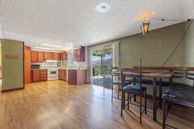 kitchen with white gas range, a textured ceiling, and light wood-type flooring