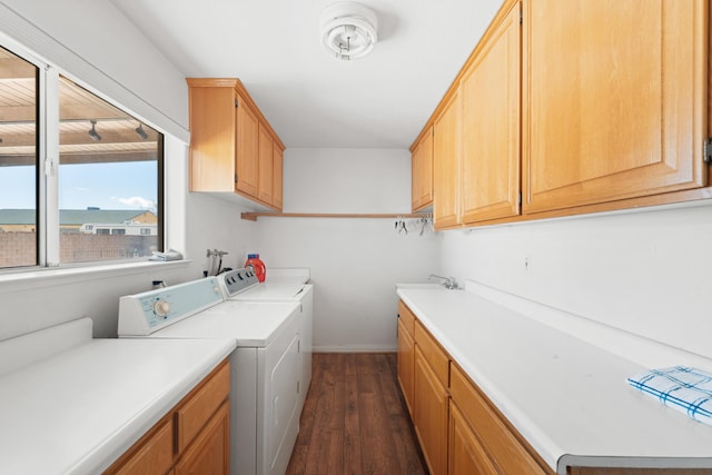 washroom featuring separate washer and dryer, a sink, baseboards, cabinet space, and dark wood-style floors