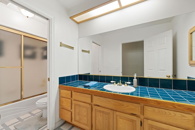 full bath with bath / shower combo with glass door, vanity, and toilet