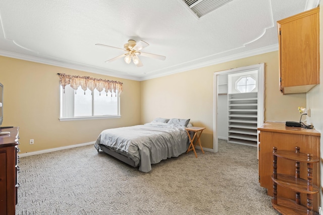 bedroom featuring a walk in closet, crown molding, light colored carpet, ceiling fan, and baseboards