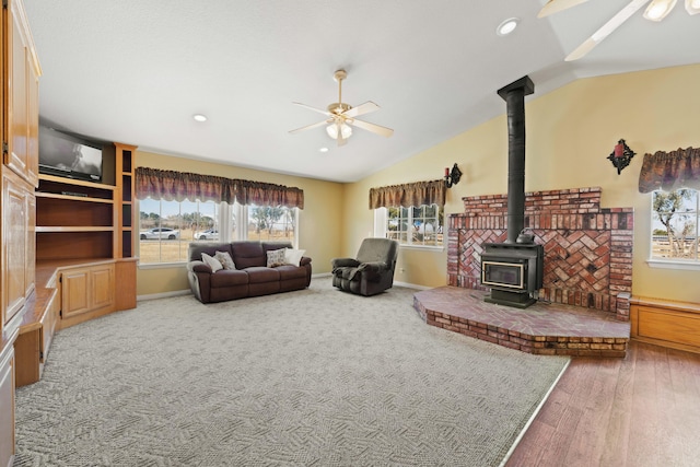 living room with recessed lighting, a ceiling fan, baseboards, vaulted ceiling, and a wood stove