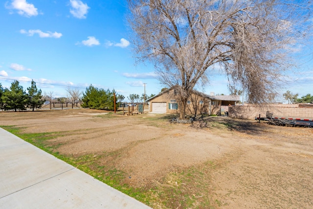 view of yard featuring dirt driveway and fence