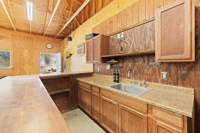 kitchen with open shelves, wooden walls, light countertops, and a sink