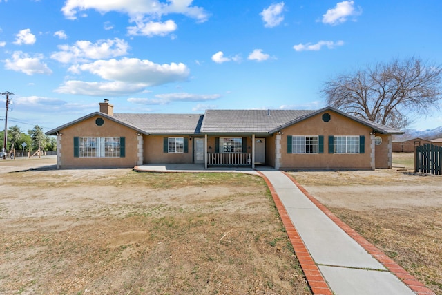 ranch-style home featuring a chimney, fence, a tiled roof, and stucco siding