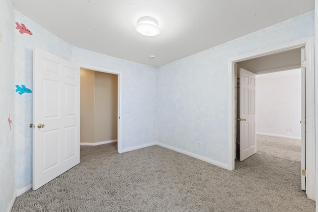 unfurnished room featuring carpet and baseboards