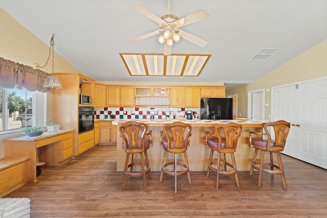 kitchen featuring lofted ceiling, light countertops, visible vents, light brown cabinets, and black appliances