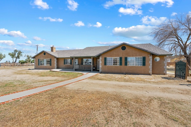 ranch-style home featuring a tiled roof, a chimney, fence, and stucco siding