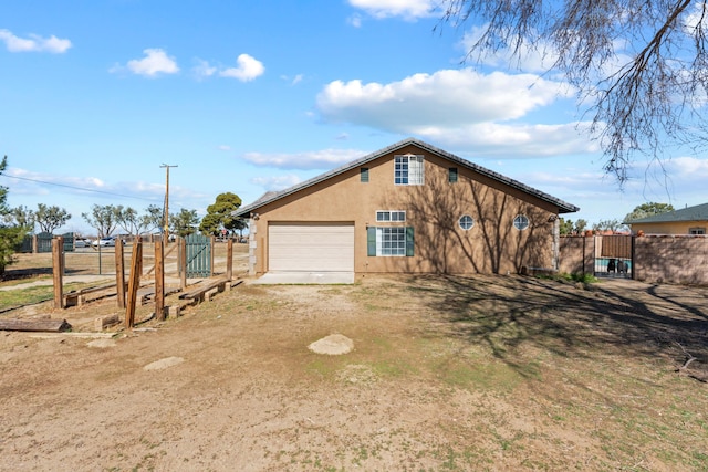 exterior space with a gate, stucco siding, driveway, and fence