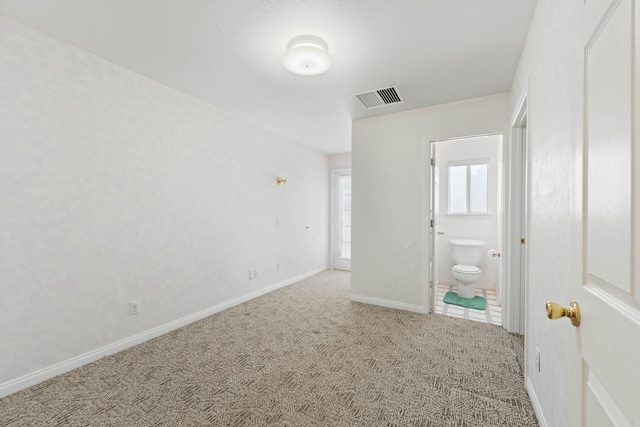 unfurnished bedroom with baseboards, visible vents, connected bathroom, and carpet flooring